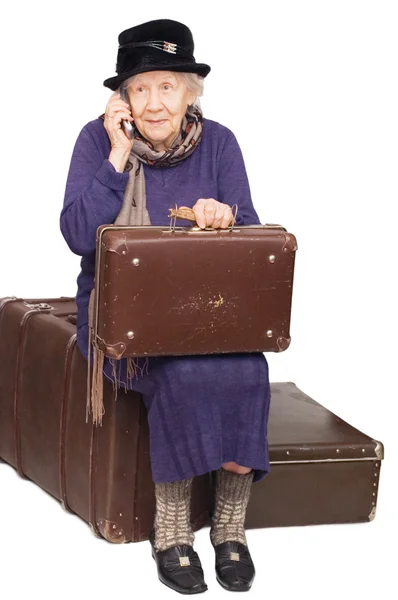 De oude dame zit op een koffer — Stockfoto