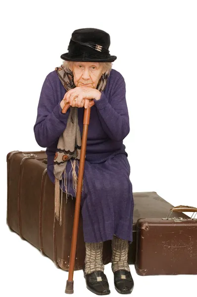 A senhora velha senta-se em uma mala — Fotografia de Stock