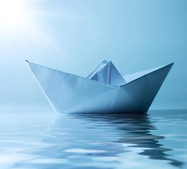 Паперовий корабель у воді та сонячно-блакитне небо — стокове фото