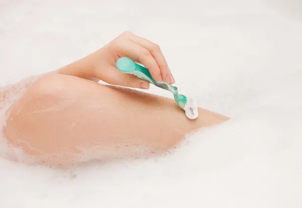 The girl shaves feet in foam — Stock Photo, Image
