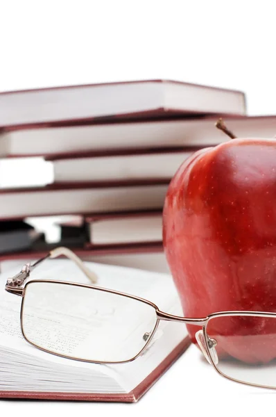Красное яблоко и очки на книге — стоковое фото