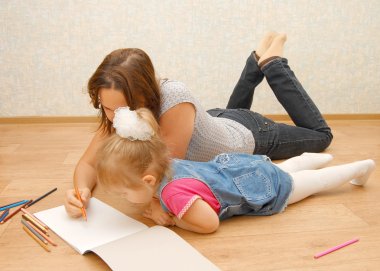 Young mother with her daughter lying on the floo clipart