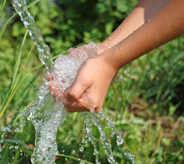 Händer att fånga rent fallande vatten på nära håll — Stockfoto