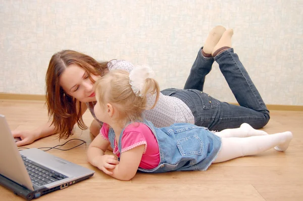 Mãe e filha com laptop no chão de madeira — Fotografia de Stock