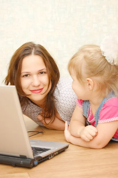 Mãe e filha com laptop no chão de madeira — Fotografia de Stock