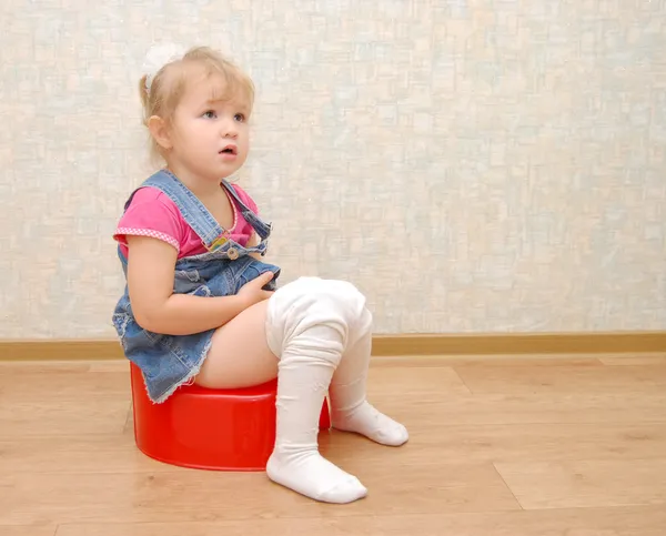Menina bonita e potty vermelho no chão de madeira — Fotografia de Stock