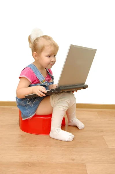 Маленька дівчинка сидить на червоному горщику з комп'ютером — стокове фото