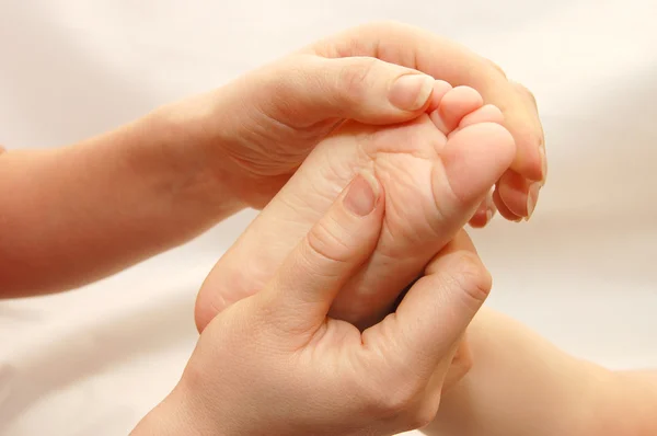 Le mani femminili massaggiano un piede di bambini — Foto Stock