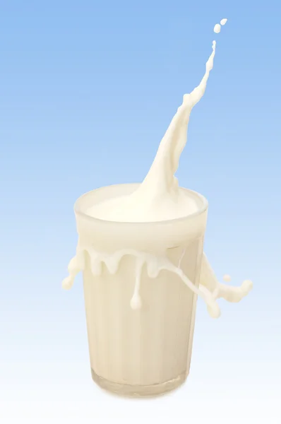 Copo de leite com respingo contra azul — Fotografia de Stock