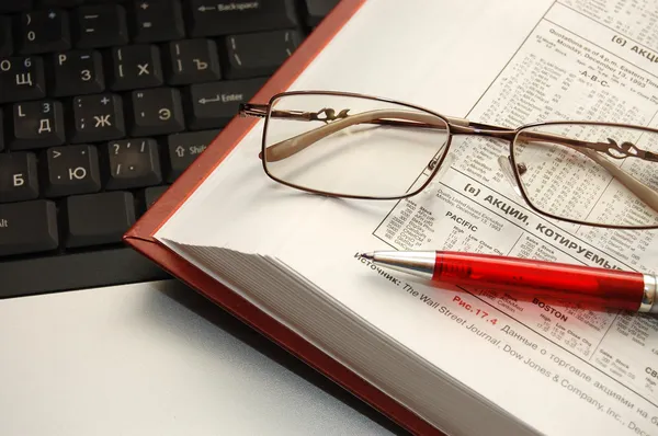 Bok, penna och glasögon låg på laptop — Stockfoto