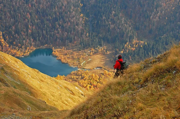 Турист в горах, смотрящий на озеро — стоковое фото