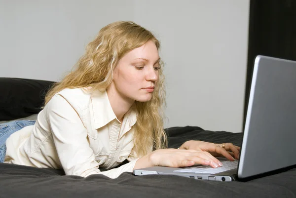 Femme couchée sur son lit avec ordinateur portable . — Photo