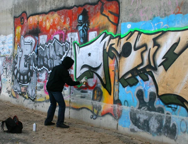 Pittore di graffi che disegna un quadro sul muro Immagine Stock