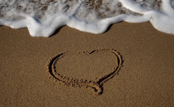 Dalga ile kum kalbinde çizilmiş — Stok fotoğraf