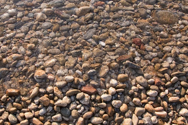Pebbles perto da água na costa — Fotografia de Stock
