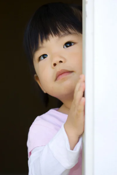 Ganska litet barn står bakom en dörr — Stockfoto