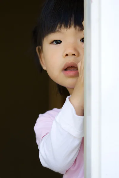 Criança bonita fica atrás de uma porta — Fotografia de Stock