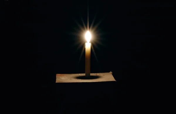 Brennende Kerze auf schwarzem Hintergrund — Stockfoto