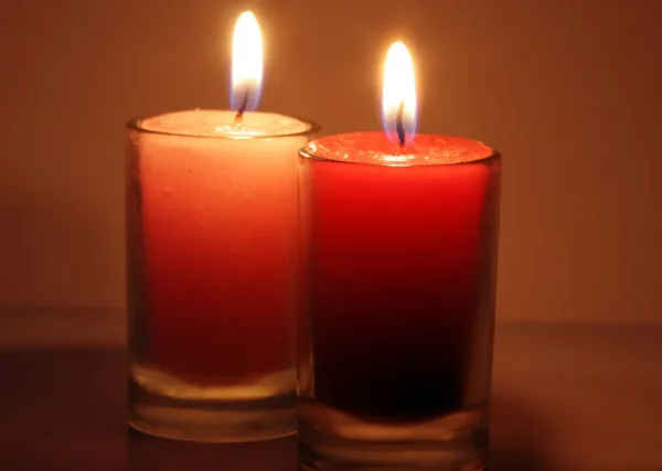 Dvě červené svíčky hořící proti — Stock fotografie