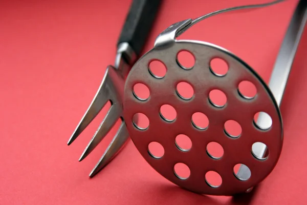 stock image Fork and potatoe-masher on red