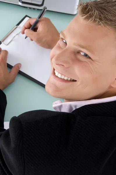 Funcionário sorridente com caneta e almofada — Fotografia de Stock