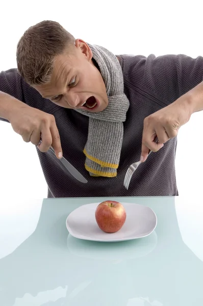 Hombre enojado con una manzana, tenedor y cuchillo — Foto de Stock