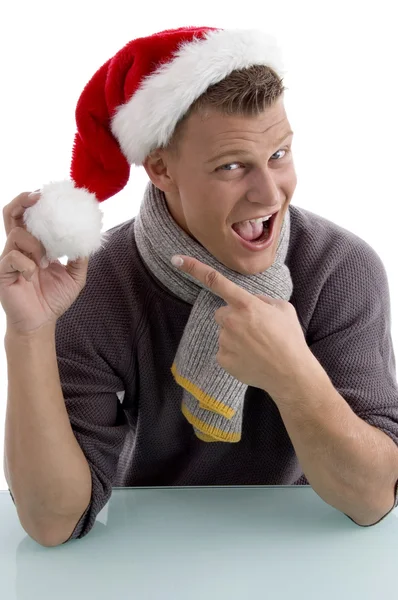 Lächelnder Mann zeigt auf Weihnachtsmütze — Stockfoto