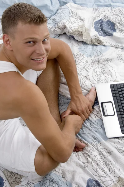 Maschio con computer portatile a letto — Foto Stock
