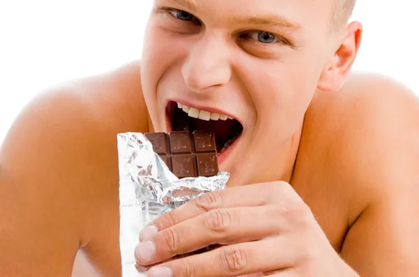 Smiling muscular man eating chocolate — Stock Photo, Image