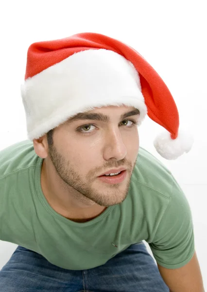 Junger Mann blickt in die Kamera mit Weihnachtsmannmütze — Stockfoto