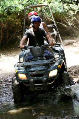 Young quad riders splashing water clipart