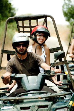 Young man drives the quad with his woman clipart