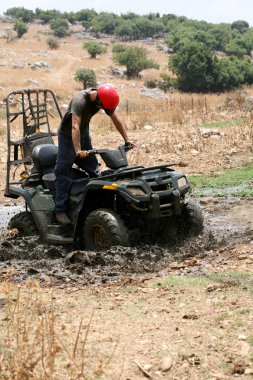 Young man badly stuck in mud with his quad bike clipart