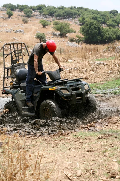 Ung man dåligt fast i lera med sin fyrhjuling — Stockfoto