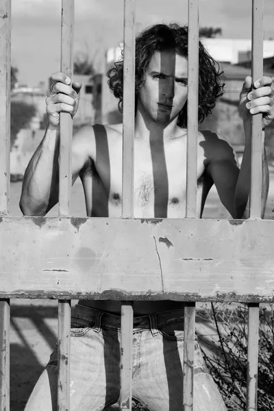 Gutaussehender hemdsloser Kerl hinter Gittern — Stockfoto