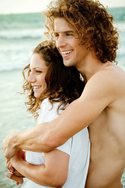 Bedårande par embracing på stranden — Stockfoto