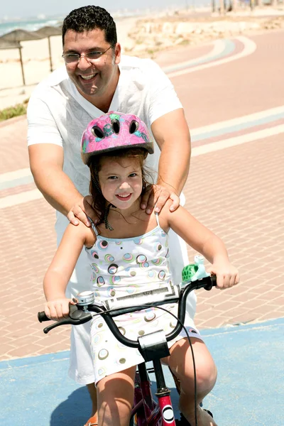 Pai apoiando filha enquanto bicicleta — Fotografia de Stock