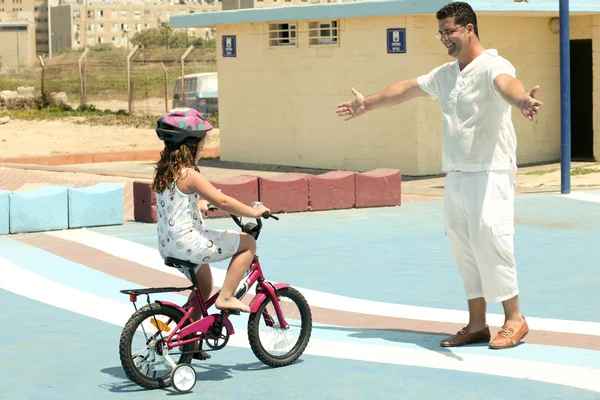 Тренер помогает ребенку научиться кататься на велосипеде — стоковое фото