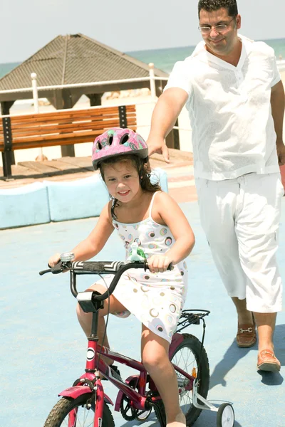 Père aidant enfant apprendre vélo équitation — Photo