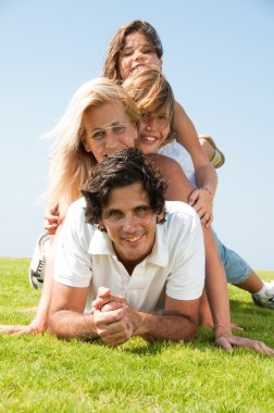 Family piled up on meadow enjoying clipart