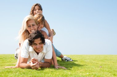 Family piled up on meadow enjoying clipart