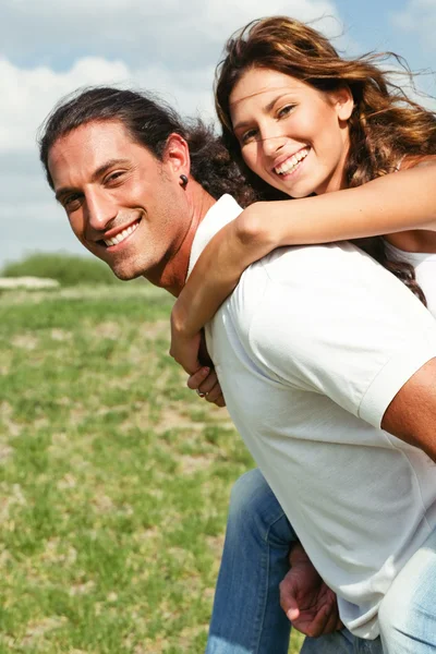 Sorrindo casal desfrutando de passeio de piggyback — Fotografia de Stock