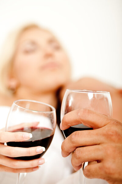 Wine glass in focus as couple make love