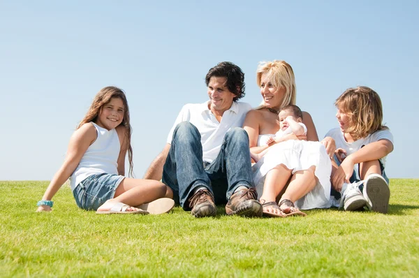 Sorrindo família relaxante na grama — Fotografia de Stock