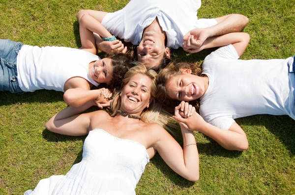 Família feliz deitado na grama — Fotografia de Stock