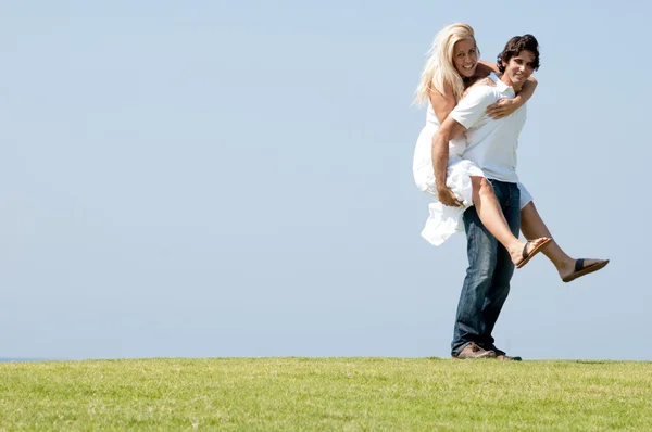 Young man giving piggy ride to woman — Stock Photo, Image