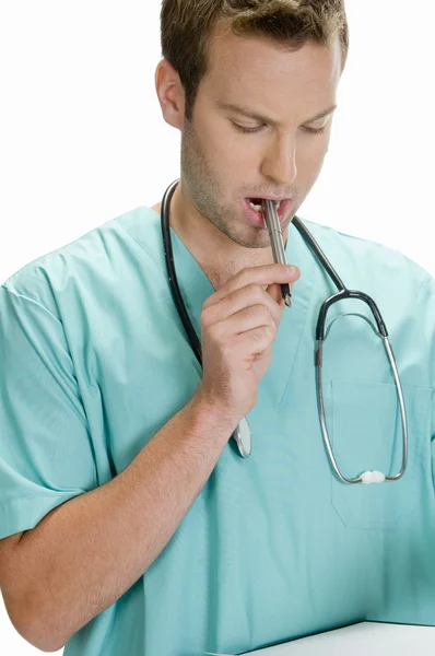 Läkare att sätta pennan i munnen — Stockfoto