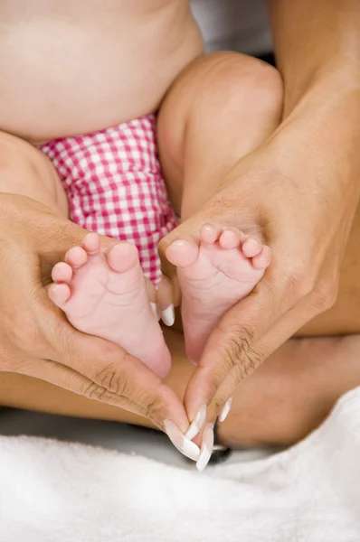 Мать держит своего ребенка за ноги — стоковое фото