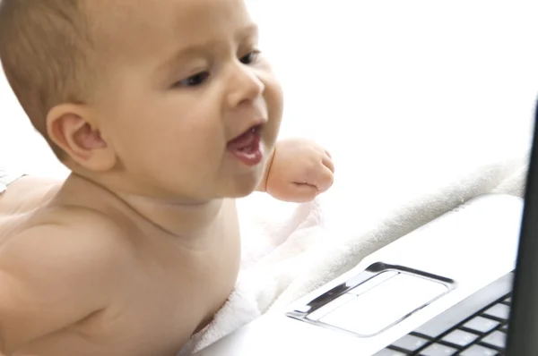 Precioso niño curioso acostado con el ordenador portátil — Foto de Stock