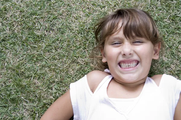 Chica joven en la hierba con los dientes apretados —  Fotos de Stock